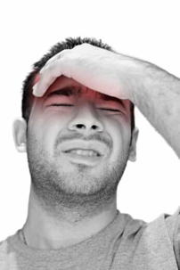young man grasping his head in pain from a migraine